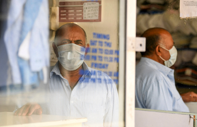 A man, wearing a protective face mask, stands inside a dry cleaner in the Emirate city of Dubai. (File/AFP)