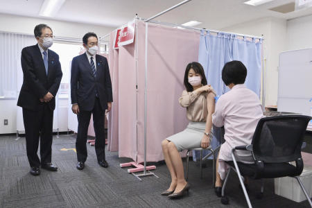 Japanese Prime Minister Fumio Kishida (second left), observes a vaccination site for staff members set up to protect against the coronavirus at the Haneda international airport in Tokyo, Saturday, Feb. 12, 2022. (AP)