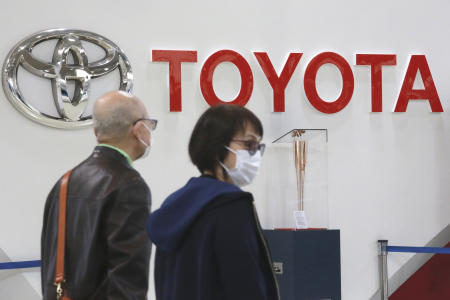 People walk past the logo of Toyota at a showroom in Tokyo, Monday, Oct. 18, 2021. (AP)