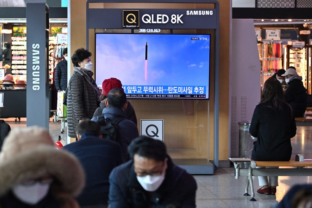 People watch a television screen showing a news broadcast with file footage of a North Korean missile test, at a railway station in Seoul on March. 5, 2022. (AFP)