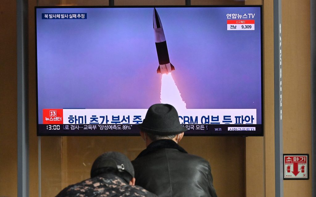 People watch a television screen showing a news broadcast with file footage of a North Korean missile test, at a railway station in Seoul on March 16, 2022. (AFP)