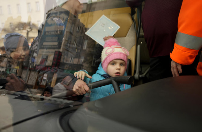 A man and two children, who are fleeing Ukraine, board a bus which will take refugees to Germany, at the train station in Przemysl, Poland on March 3, 2022. (AP)