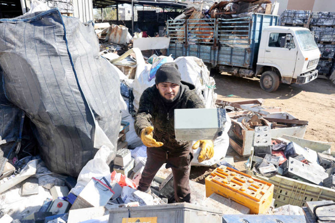 A Palestinian man picks discarded batteries to resell for recycling, at a scrapyard in Khan Yunis in the southern Gaza Strip, on February 14, 2022. (AFP)