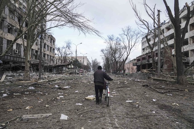 A man walks with a bicycle in a street damaged by shelling in Mariupol, Ukraine, Thursday, March 10, 2022. (AP)