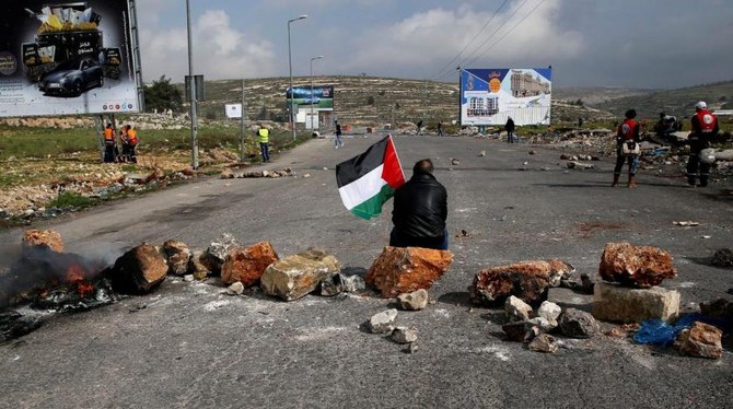 A demonstrator holds a Palestinian flag as he sits during clashes with Israeli troops near the settlement of Beit El, near Ramallah. (Reuters)