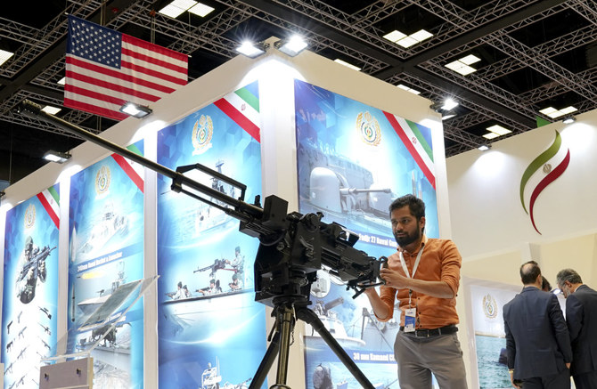 A visitor stands behind a machine gun in Iran's Pavilion at the DIMDEX exhibition in Doha, Qatar, on March 23, 2022. (AP Photo/Lujain Jo)