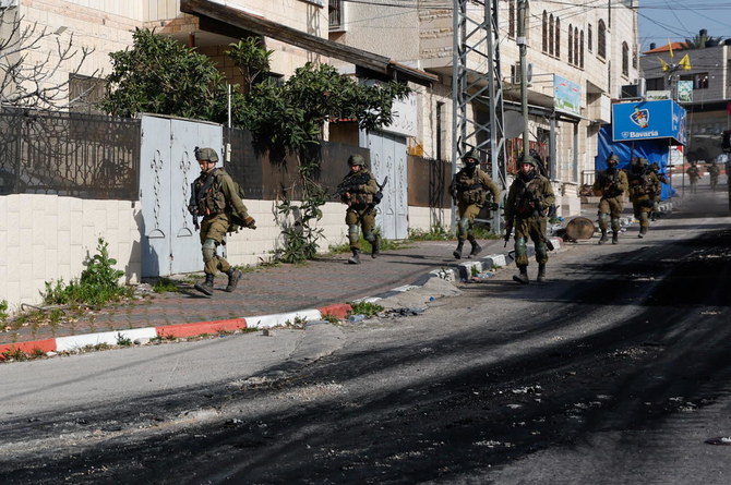 Israeli soldiers run during a raid in Jenin in the Israeli-occupied West Bank on March 30, 2022. (Reuters)