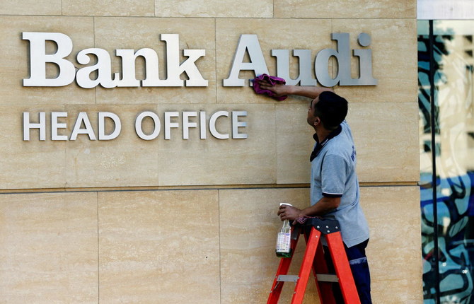 A worker cleans the logo of Bank Audi in Beirut, Lebanon. (Reuters)