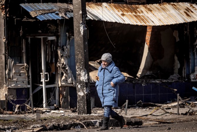 A Ukrainian resident walks in front of destroyed buildings in the northeastern city of Trostyanets on March 29, 2022. (AFP)
