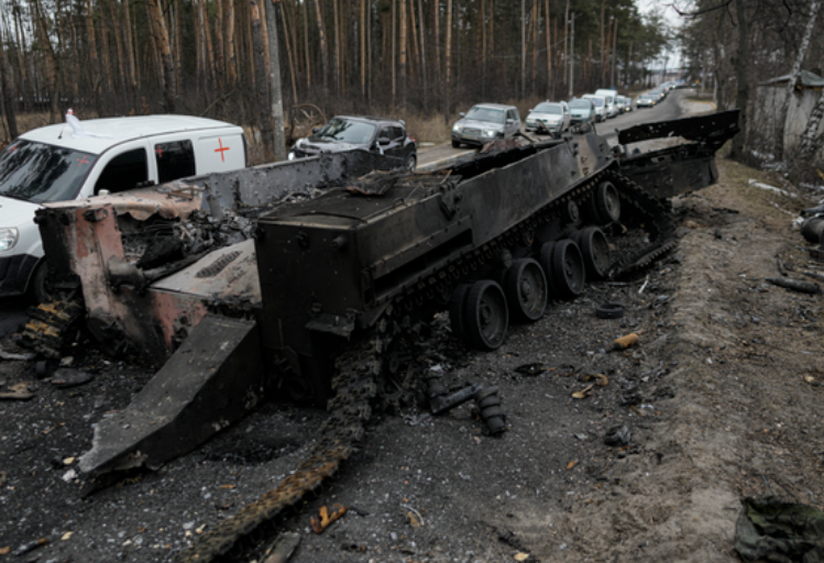 Cars drive past a destroyed Russian tank as a convoy of vehicles evacuating civilians leaves Irpin, on the outskirts of Kyiv, Ukraine, on March 9, 2022. (AP)