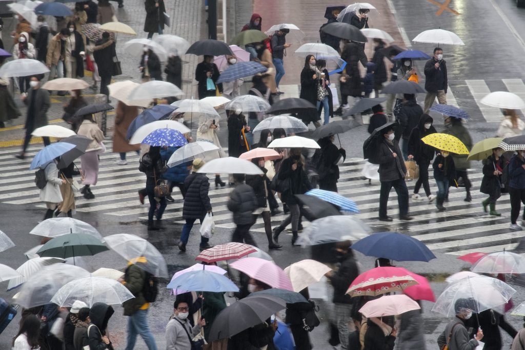 People walk at Shibuya crossing in rainy Tokyo on February 13, 2022 amid the coronavirus pandemic. (AFP)