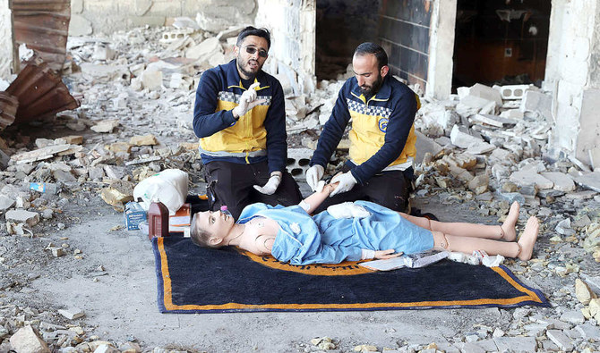 Members of the Syrian civil defense known as the White Helmets use a dummy to demonstrate their rescue skills during a video shoot, for an instructive film intended for Ukrainian rescuers, in the war-ravaged Syrian town of Ariha, Idlib province. (AFP)