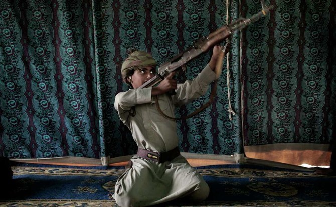 Kahlan, a 12-year-old former child soldier with the Houthis, demonstrates how to use a weapon at a camp for displaced persons where he took shelter with his family in Marib, July 27, 2018. (AP Photo)