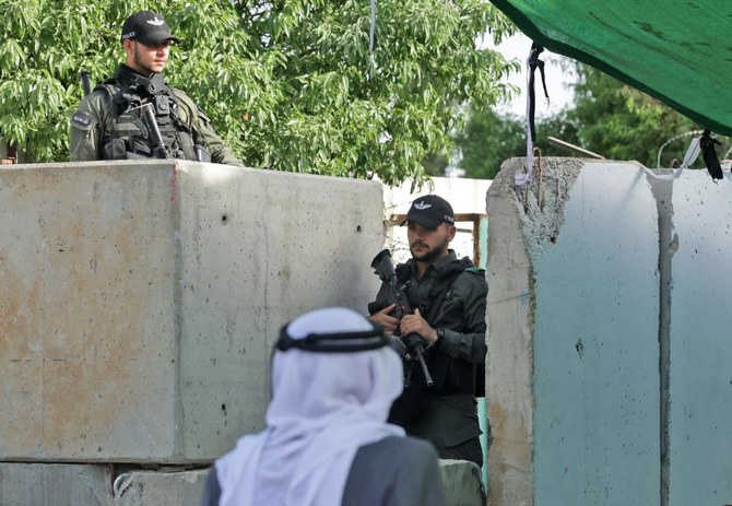 Israeli security forces keep watch as Palestinians cross a checkpoint to reach Jerusalem for last Friday prayers of Ramadan in the Al-Aqsa mosque compound on April 29, 2022. (AFP)