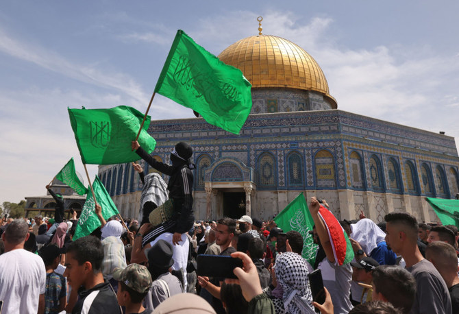 Palestinians wave national and Islamic flags inside Jerusalem's Al-Aqsa Mosque complex following prayers of the third Friday of the Muslim holy month of Ramadan, on April 22, 2022. (AFP)