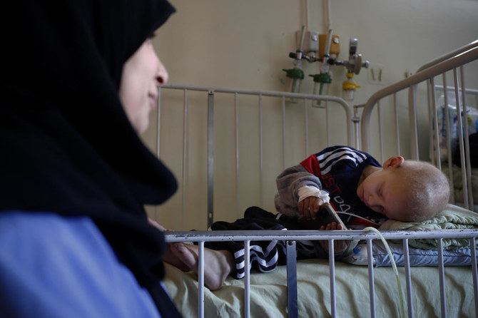 A woman watches over her child receiving treatment at the cancer ward of the Children's Hospital in Damascus, Syria, Monday, March. 7, 2022. (AP)
