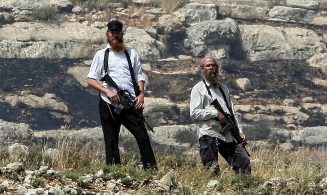 Armed settlers from the hardline Jewish settlement of Yitzhar patrol a cliff edge. (AFP)