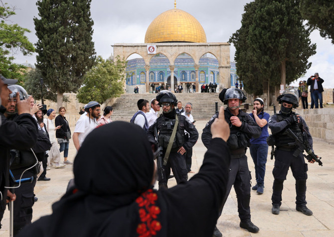 A Palestinian woman gestures as Israeli police accompany a group of Jewish visitors past the Dome of the Rock mosque at the Al-Aqsa mosque compound in the Old City of Jerusalem on May 5, 2022. (AFP)