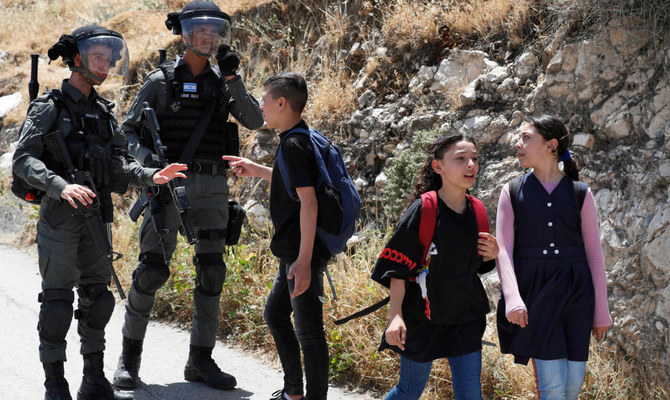 A Palestinian youth talks to Israeli border guards near the site where Israeli machinery demolish a Palestinian house in the Arab east Jerusalem neighbourhood of Silwan on May 10, 2022. (AFP)