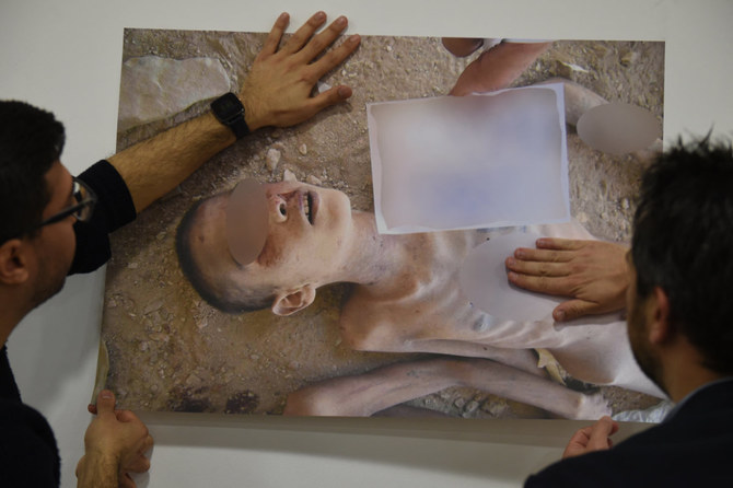A photo of a torture victim taken by a former military policeman of the Syrian army are shown by Syrian activists during a rally in Geneva on March 17, 2016 in Geneva. (AFP)