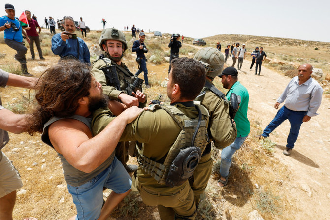 An Israeli settler scuffles with a Palestinian activist as Israeli soldiers hold him back during a protest in Masafer Yatta, Israeli-occupied West Bank, on May 13, 2022. (REUTERS/Mussa Qawasma)