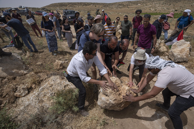 Palestinian, Israeli and foreign peace activists clear a road block near the Jewish settlement of Mezbi Yair, Masafer Yatta, West Bank, on May 13, 2022. (AP Photo/Nasser Nasser)