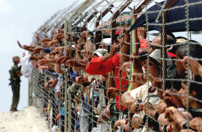 Palestinian refugees living in Lebanon gather at the barbed wire border fence between Lebanon and Israel to meet with their relatives in Dhayra as an Israeli soldier stands guard. (AFP)