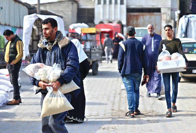 Palestinians collect food aid at a distribution center run by the UN Relief and Works Agency in Gaza City. (File/AFP)