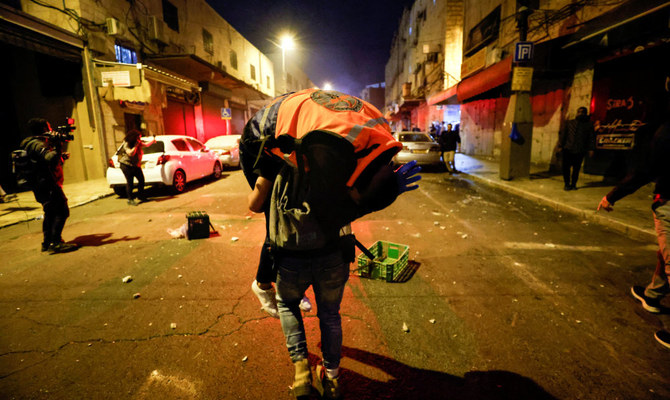 A man carries an injured rescue personnel during clashes between Israeli security forces and Palestinians around the funeral of Waleed Al-Shareef outside Jerusalem's Old City May 16, 2022. (Reuters)