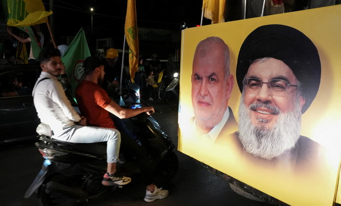 Supporters carry Hezbollah and Amal Movement flags beside a poster depicting Hezbollah chief Hassan Nasrallah and head of Hezbollah’s parliamentary bloc Mohamed Raad during Lebanon’s parliamentary election on Sunday. (Reuters)