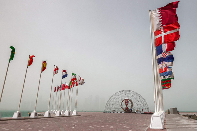 The flags of nations taking part in the Qatar 2022 FIFA World Cup fly Qatar's capital Doha during a heavy dust storm on May 17, 2022 as the skyline behind is obscured in the haze. (AFP)