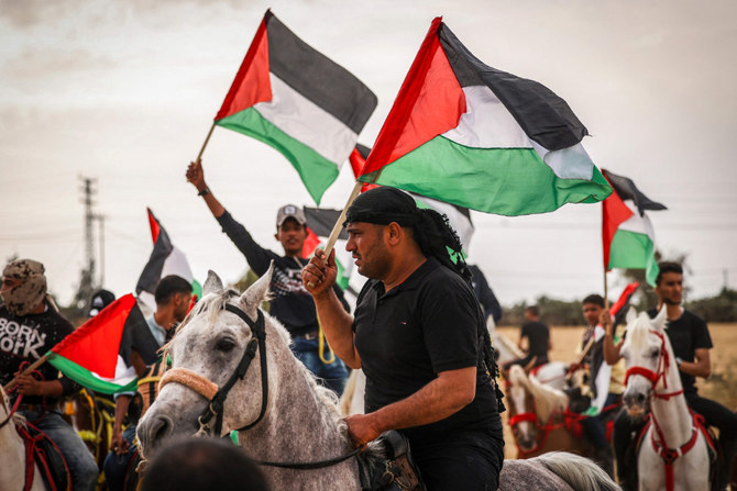 Palestinians waving their national flags take part in a rally on the 74th anniversary of the Nakba, east of Gaza City. (AFP)