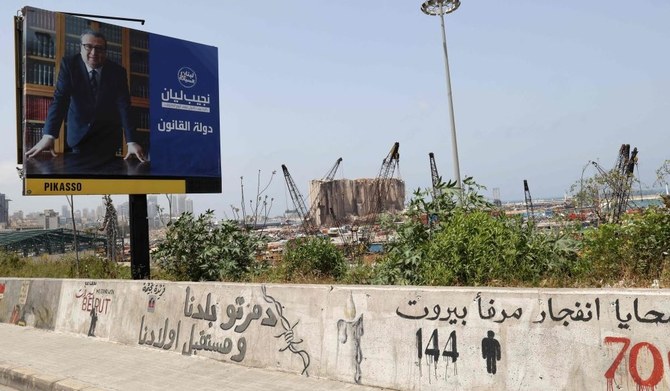 An electoral billboard for Najib Lyan, a candidate in the Lebanese parliamentary elections, next to Beirut Port’s damaged grain silos, Beirut, Lebanon, May 1, 2022. (AFP)