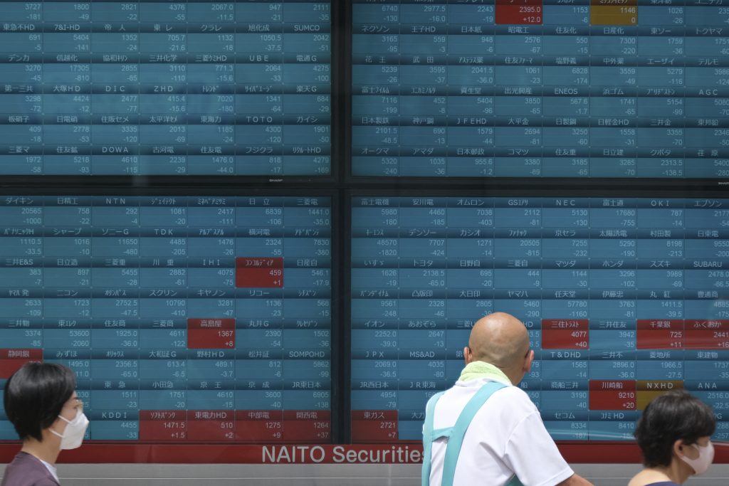 Pedestrians walk past an electronic quotation board displaying stock prices of the benchmark Nikkei 225 index in Tokyo. (AFP)