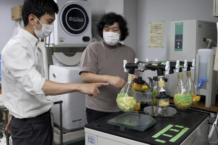Tokyo University researchers Yuya Sakai (left) and Kota Machida, check on dried vegetables and fruit peels before pulverizing them to particles at their university laboratory in Tokyo, on May 26, 2022. (AP)