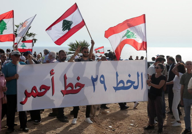 Demonstrators carry a banner that reads ” The Line 29 is a red line” and flags during a protest against Israeli gas extraction from a maritime field that Lebanon says falls in disputed waters in Naqoura, southern Lebanon on Saturday. (Reuters)