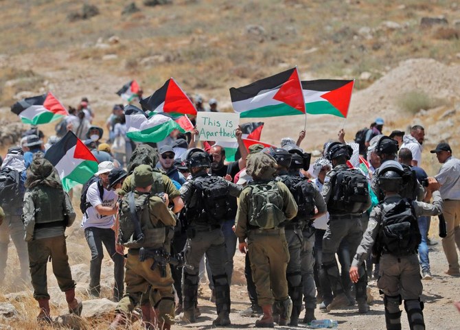 Israeli security forces surround demonstrators raising Palestinian flags, as Palestinian, left-wing, Israeli and foreign activists gather to protest against a High Court decision to evict Palestinian communities from Fire Zone 918, on June 10, 2022. (AFP)