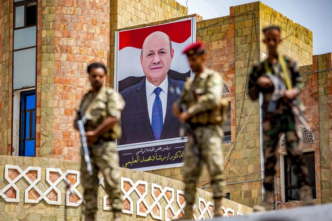 Yemeni soldiers stand guard before a poster showing the chairman of the Presidential Council Rashad Al-Alimi, while on guard duty during a demonstration. (File/AFP)