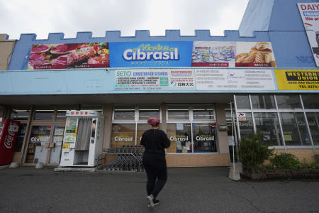 A woman walks towards a supermarket offering food, drinks and items ordinarily found in Brazil, in a town called Oizumi, about 90 kilometers (55 miles) northwest of Tokyo, Tuesday, May 31, 2022. (AP)