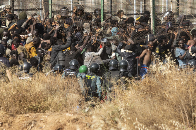 Migrants arrive on Spanish ground after crossing the fences separating the Spanish enclave of Melilla from Morocco in Melilla, on Friday. (AP)