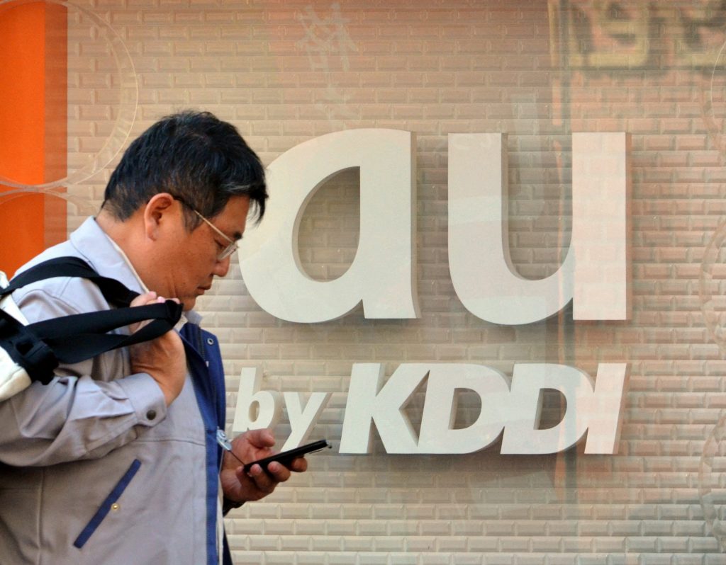 A pedestrian uses his mobile phone before a KDDI mobile phone shop in Tokyo. (AFP)