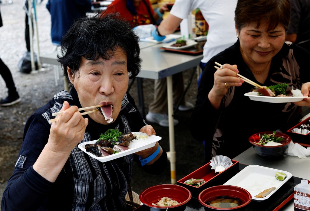 A participant in the katsuo matsuri festival eats a piece of katsuo no tataki (seared raw skipjack tuna), in Nakatosa Town, Kochi Prefecture, Japan, May 14, 2022. (AFP)