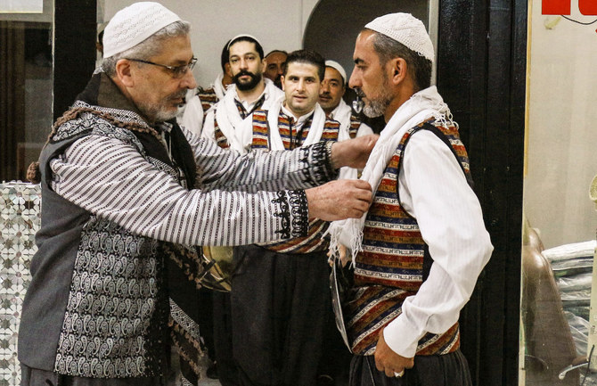 Moutaz Boulad, leader of the ‘Bab Al-Hara’ traditional Syrian dance troupe, assists members as they gear up to perform at a celebration in Jordan’s capital Amman. (AFP)