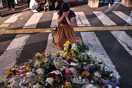 A woman reacts in front of a makeshift memorial where people place flowers at the scene outside Yamato-Saidaiji Station in Nara where former Japanese prime minister Shinzo Abe was shot earlier in the day on July 8, 2022. (AFP)