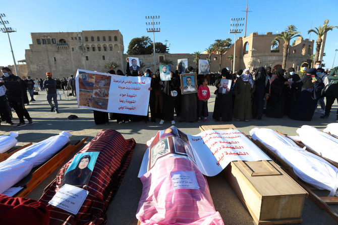 Mourners show portraits near bodies which were exhumed from a mass grave in Tarhouna before getting reburied in Tripoli, Libya. (Reuters)