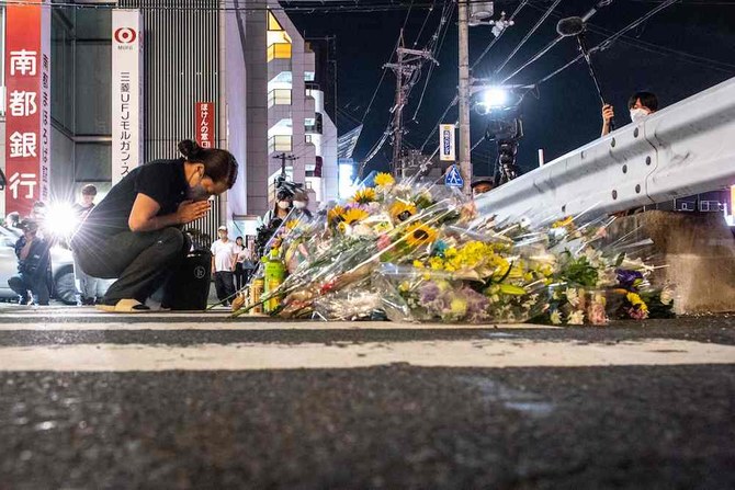 People place flowers at the scene outside Yamato-Saidaiji Station in Nara where former Japanese PM Shinzo Abe was shot on July 8, 2022. (AFP)