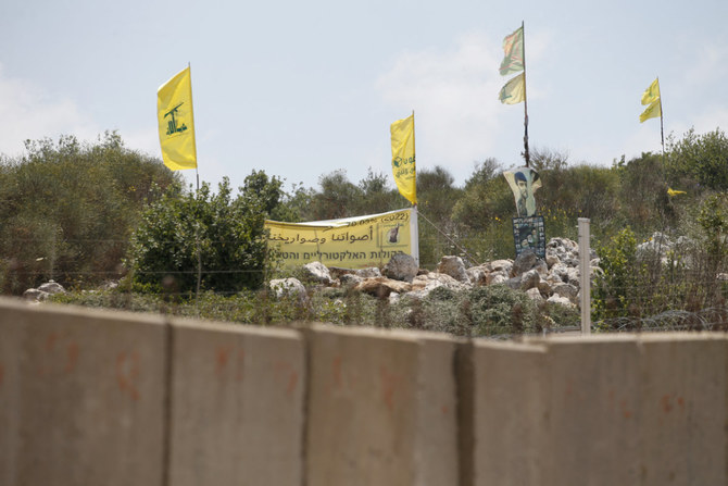 A pro-Hezbollah placard and flags stand on Lebanon's border with Israel on July 2, 2022. (AFP)