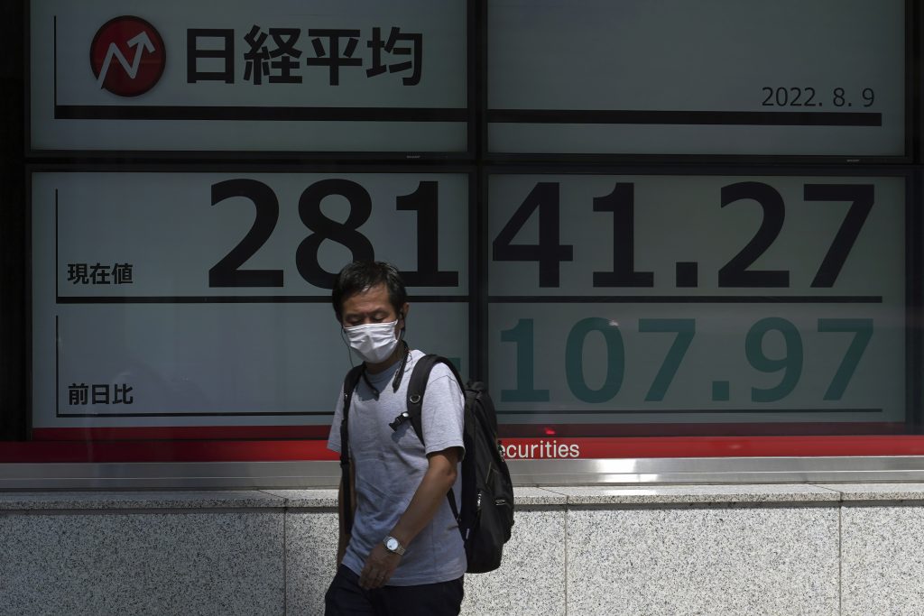 A person wearing a protective mask walks in front of an electronic stock board showing Japan's Nikkei 225 index at a securities firm in Tokyo, Aug. 9, 2022. (File photo/AP)
