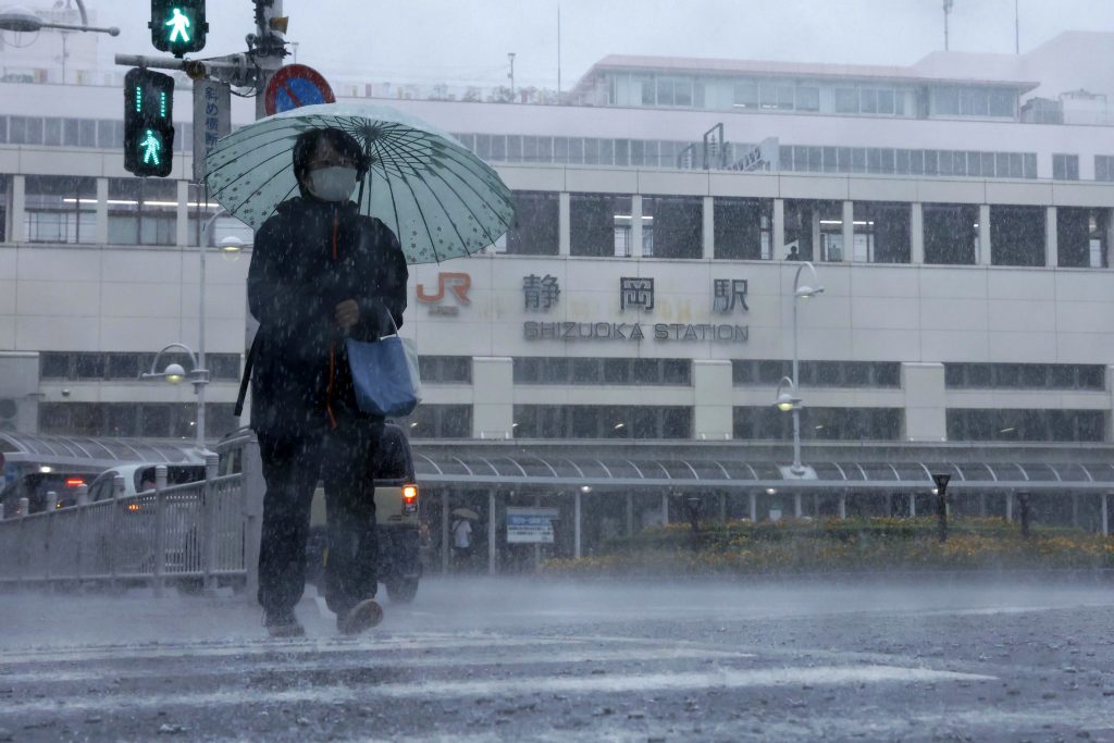 A person walks in the rain in front of a station in Shizuoka, west of Tokyo, Aug. 13, 2022. (File photo/Kyodo News via AP)