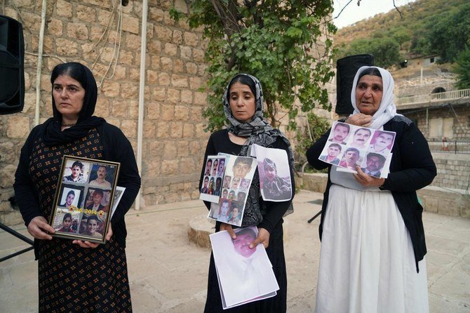 Women members of Iraq’s Yazidi community hold photos of victims of the August 2014 massacre carried out in the Sinjar region by Daesh militants on Aug. 2, 2022. (AFP)
